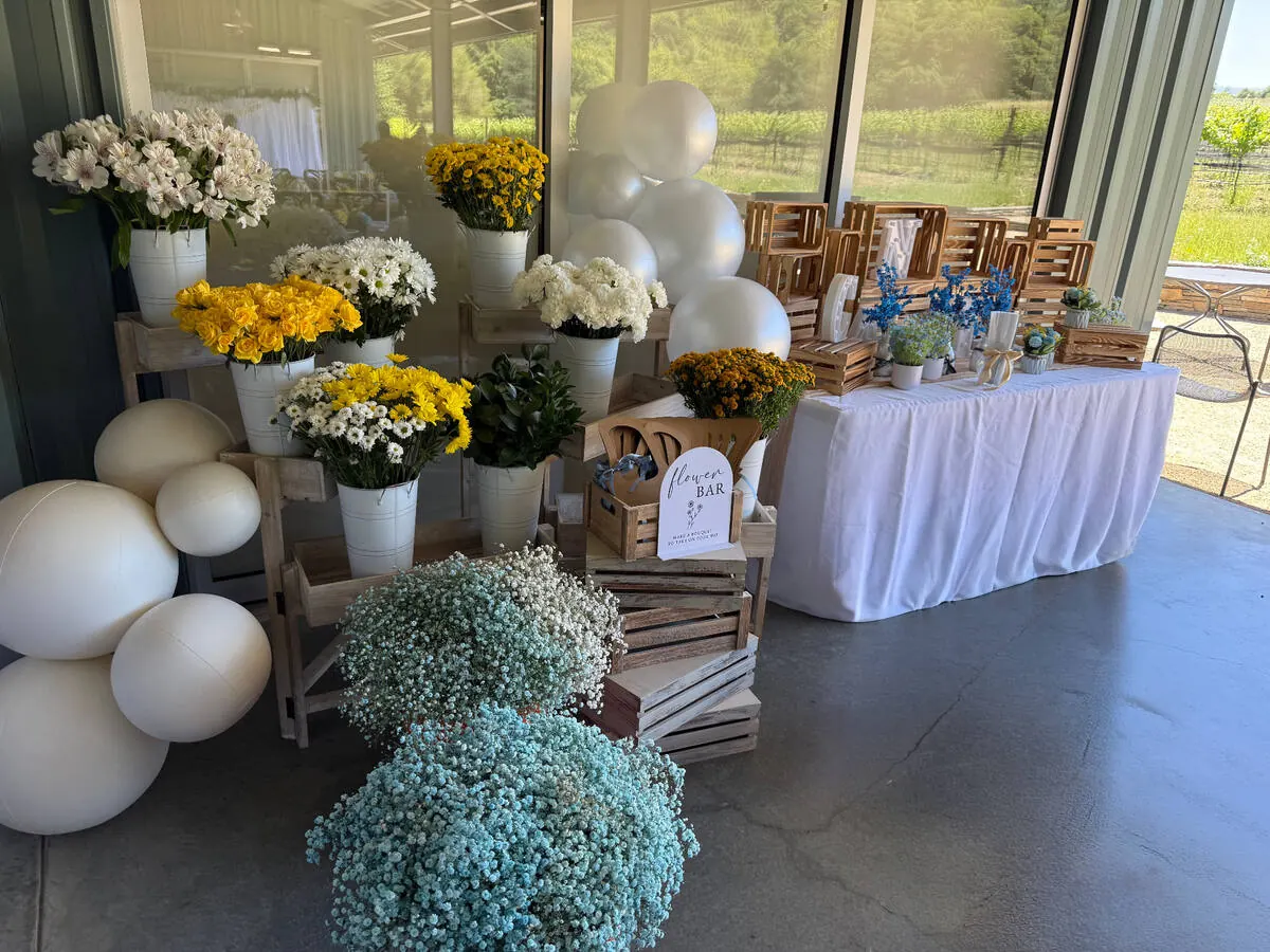 Bloom bar with buckets of yellow roses, daisies and baby's breath set for guests to wrap take-home bouquets — signature bloom bar for Tracy catering events